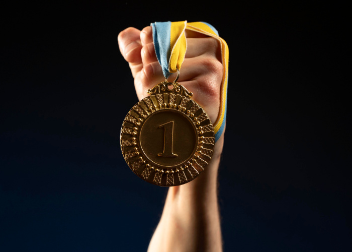 Fist holding a first place medal. Image by freepik.